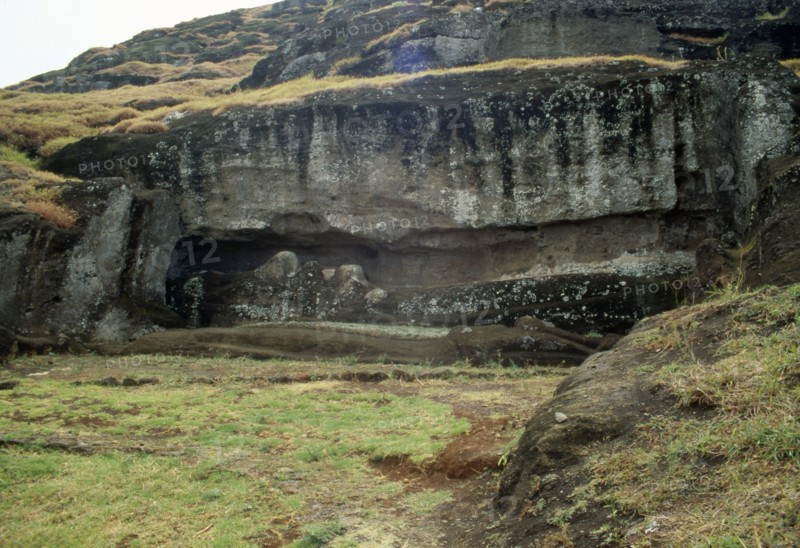 Two giant Easter Island moai statues lying head-to-foot, unfinished, and still attached to the bedrock of the volcanic Rano Raraku quarry