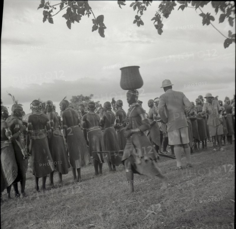 Woman going to inyangi, in front of ch. J. and dancers