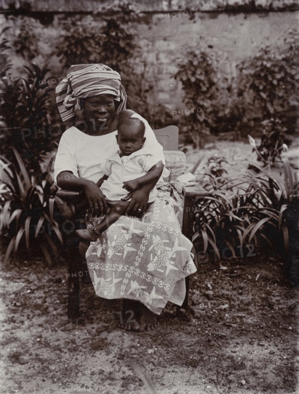 Portrait of seated African woman holding baby
