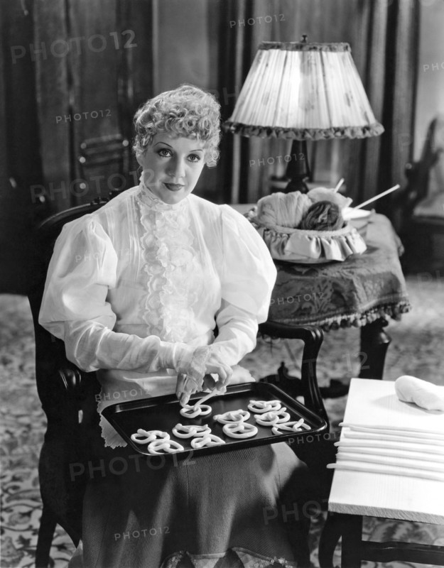 United States:   c. 1920.
A woman making pretzels on a baking sheet for baking.