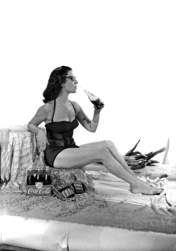 United States: c. 1947.
A set for a photo shoot for a Coca Cola ad, complete with beach sand and a pretty woman in a bathing suit.
