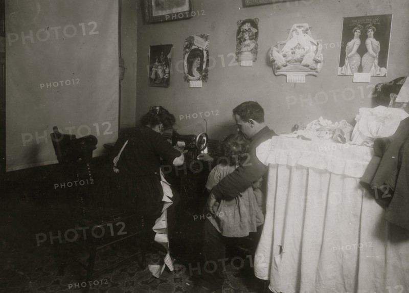 Italian woman sits at her Singer Sewing Machine making clothes for dolls  1911