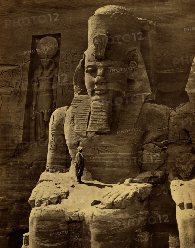 View of colossal figure, probably Ramses II, carved into rock that is the Great Temple at Abu Sunbul, Egypt. 1865