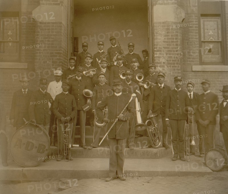 African American band posed on steps to brick building 1899