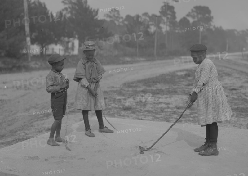 African American Children pretend to play golf on country road 1905
