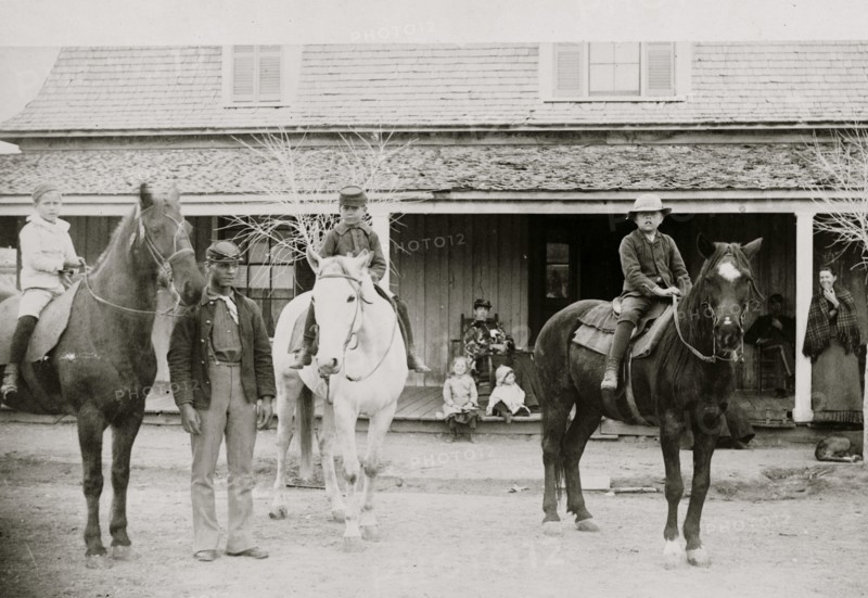 Afro-American enlisted man standing by three officers' children on horseback, Fort Verde, Arizona 1886