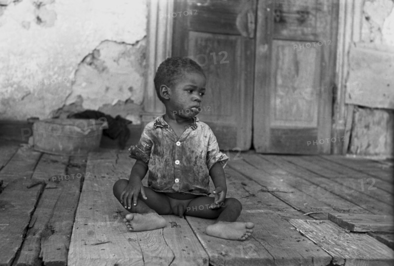 Black child on porch of dilapidated Trepagnier plantation near Norco, Louisiana 1938