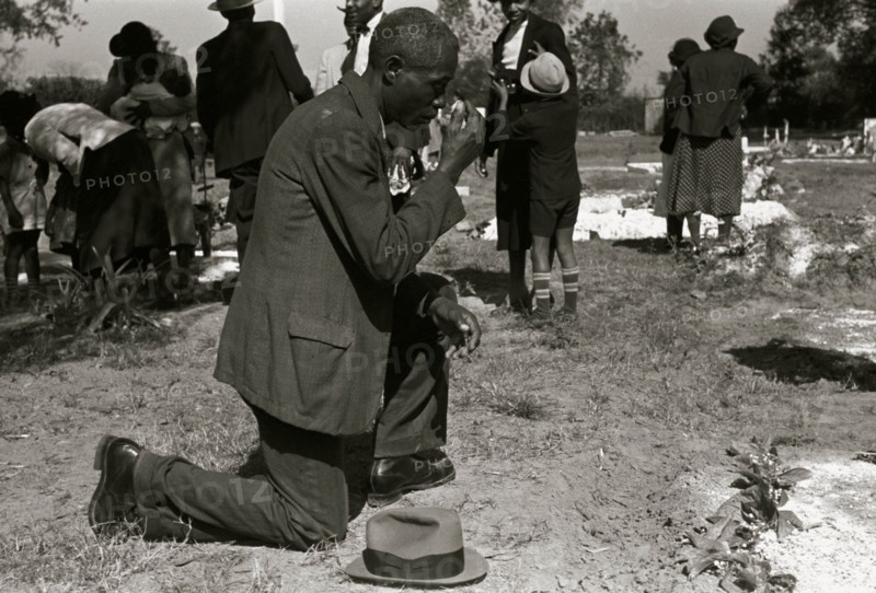 Black crossing himself and praying over grave of relative in cemetery, All Saints' Day, New Roads, Louisiana 1938