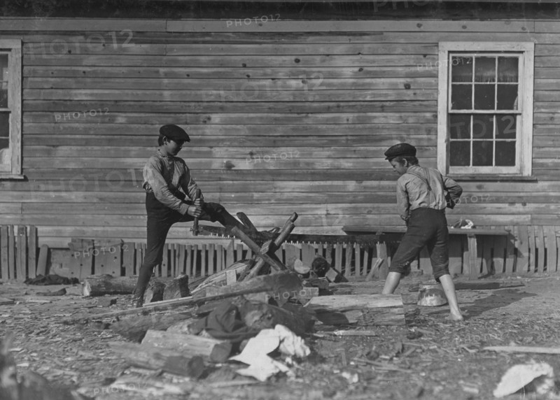 Two young boys from the Cotton Mill use a large crosscut saw 1908