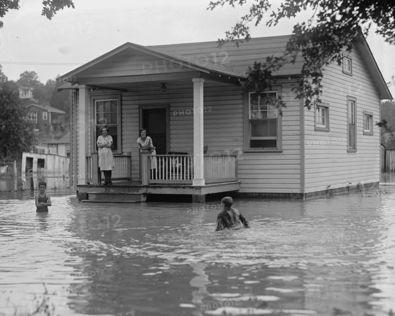 Children on porch of house surrounded by flood 1922