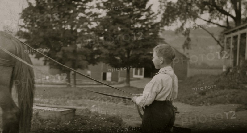Eight-year old Jack carrying cans of milk on stone boat. This involves some heavy lifting 1915