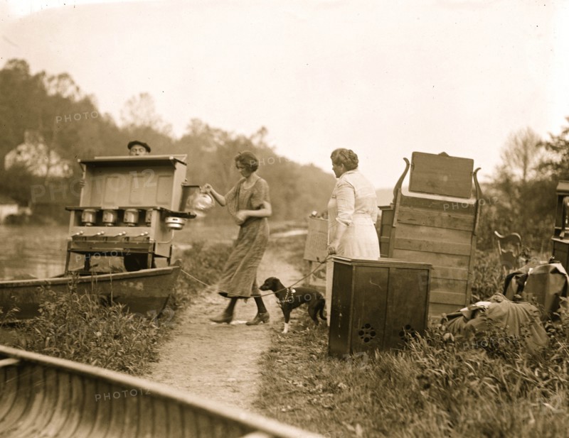 Folks carry a range out their home to escape rising water in a flood; a women holds their pet dog on a  leash 1924