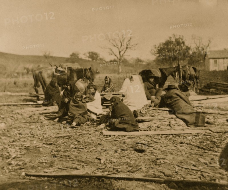 Group of Winnebago Indians seated on ground and logs 1864