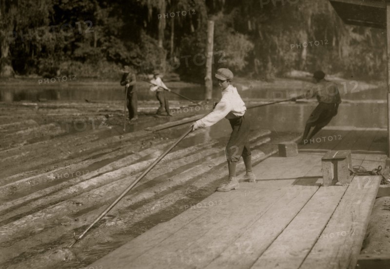 Hard work and dangerous. This "river-boy" Lyman Frugia. Poles the heavy logs into the incline that takes them up to the mill.  1914
