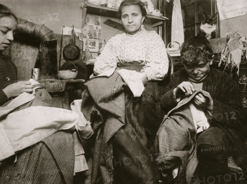 High up on the top floor of a rickety tenements, immigrants, this mother and her two children were living in a tiny one room, and were finishing garments.  1924