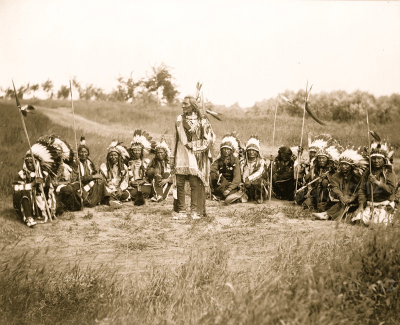 Chief Little Wound in council with other Indians, wearing feather headdresses 1899