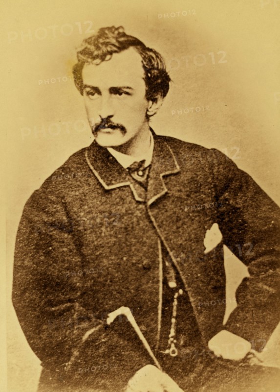 John Wilkes Booth, half-length portrait, facing left and holding a cane 1860