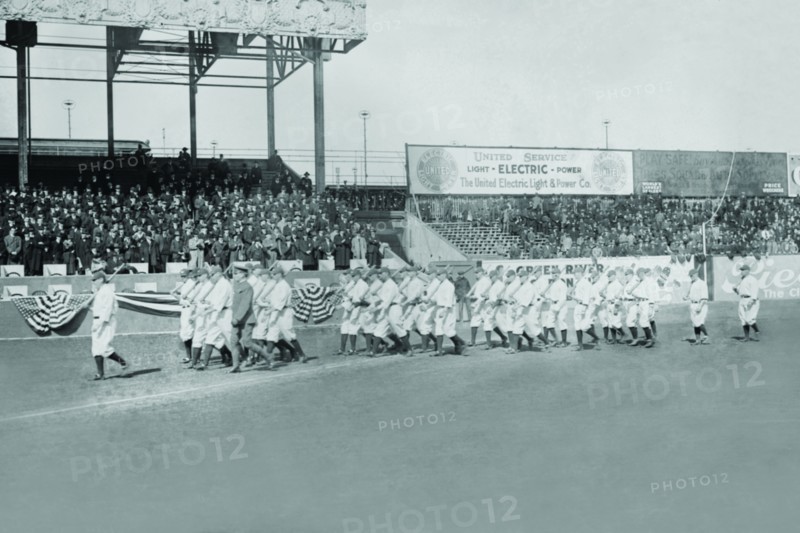 New York Yankees show support for the Troops in World War I by marching around the stadium on baseball uniforms and carrying rifles over their shoulders. 1917