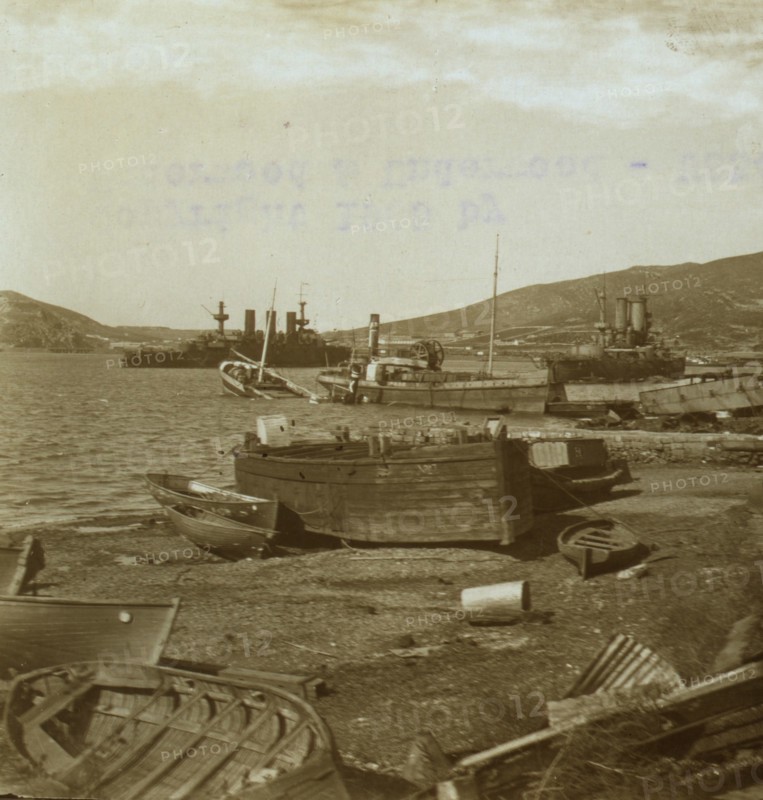 Small boats on shore and warships in harbor at Port Arthur 1905
