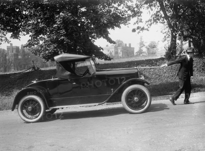 Suited man looks like he is pulling a coupe up an incline by a string