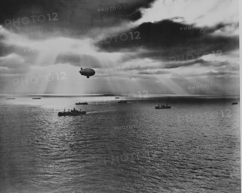 Sunset over the Atlantic finds another United Nations convoy moving peacefully towards it destination. A U.S. Navy blimp, hovering watchfully overhead, is on the lookout for any sign of enemy submarines 1943