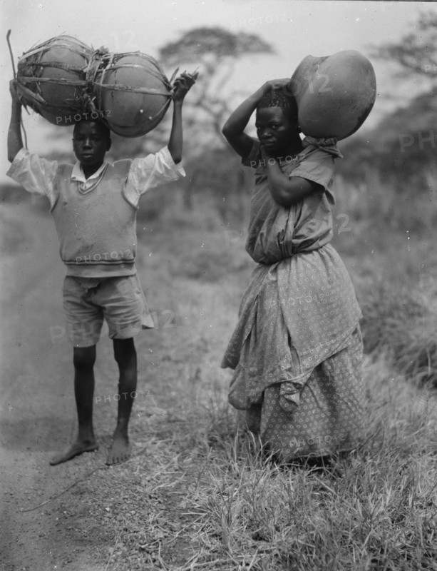 Uganda boy and girl carrying jars 1936
