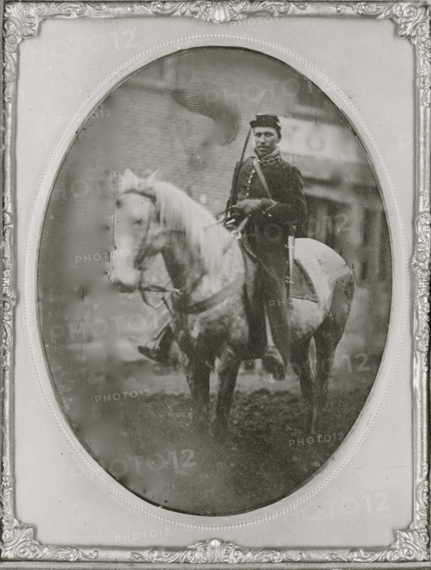 Unidentified African American soldier seated on horseback, facing left. 1865