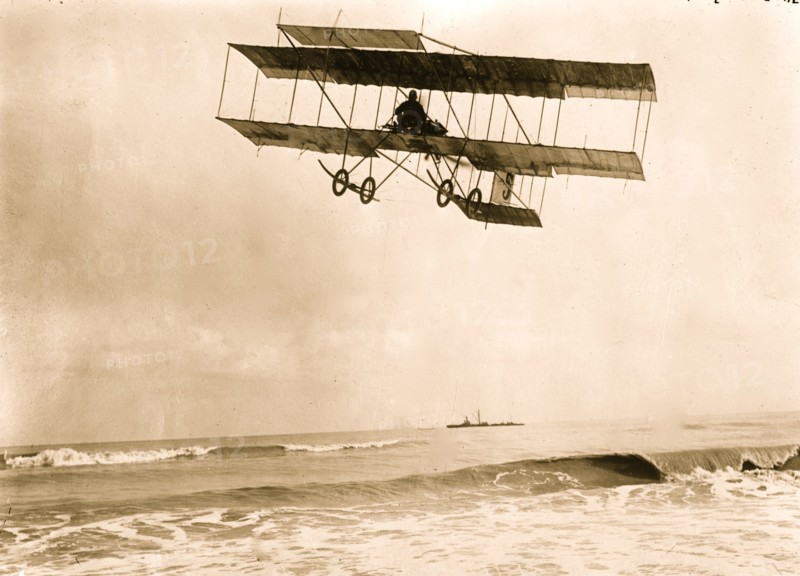 M. Van den Born flying above the sea. A ship is on the horizon