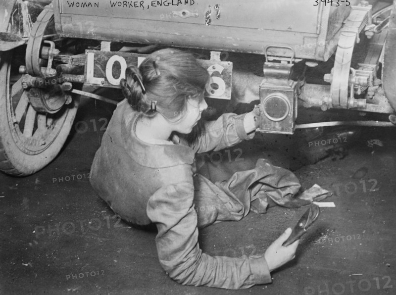 Woman mechanic in England during the great war; show works under a vehicle 1917
