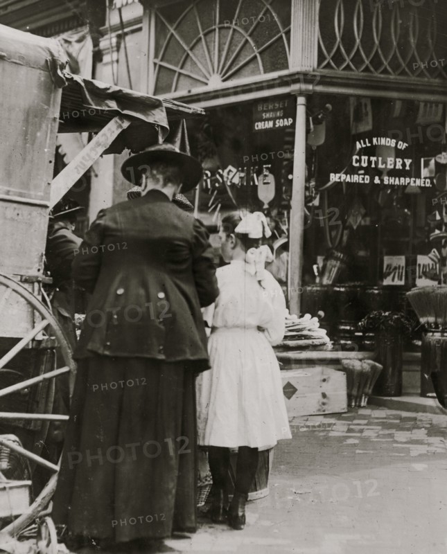 Young vendor sells goods outside of a cutlery store 1910
