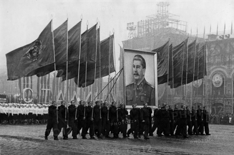 A demonstration / parade of the working people in red square in moscow on november 7, 1950, the sportsmen are carrying soviet flags and an image of stalin.