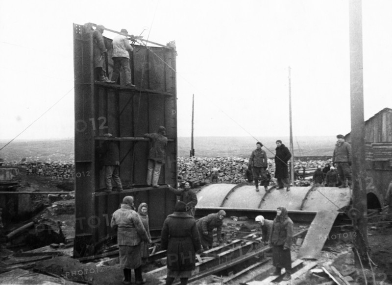 Post-war donbass heals it's wounds, setting up a cylindrical head-frame, designed by engineer zherbin, at the dzerzhinsky colliery no, 12 in donbass, ussr, 1940s.