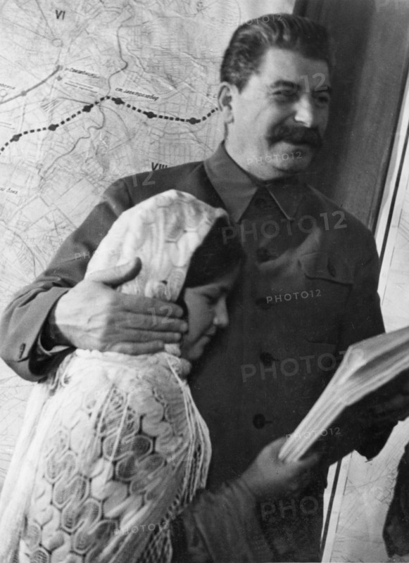 Propaganda photo of josef stalin as benevolent father figure with eleven year old mamlakat nakhangova, a schoolgirl from the lakhuti collective farm, stalinabad region, tajikistan soviet republic, kremlin palace, moscow, ussr, december 1935.