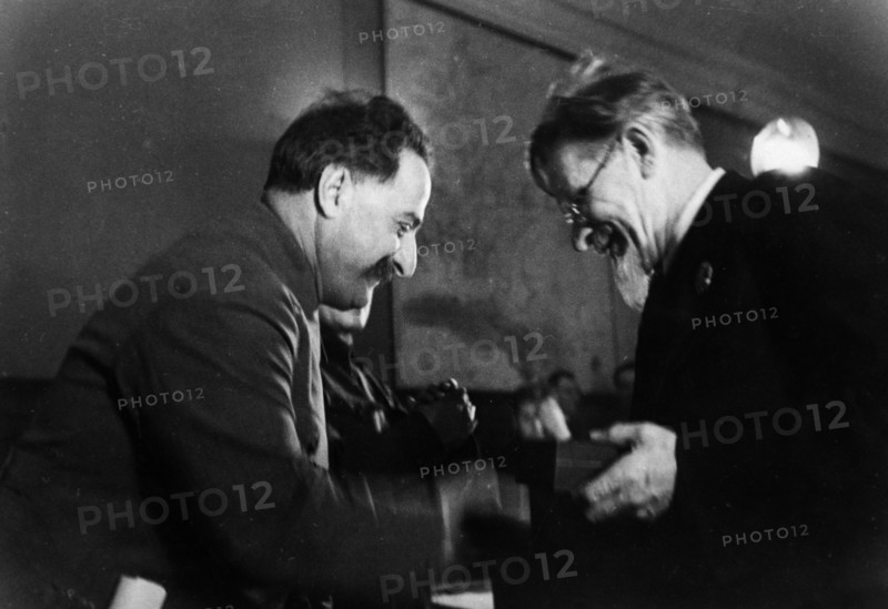 M, i, kalinin, president of the central executive committee of the ussr, awarding the order of the red banner of labor to grigoriy konstantinovich ordzhonikidze (sergo ordzhonikidze), the people's commissar of heavy industry, for over-fulfilling the production plan of 1935.