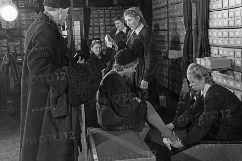 A woman trying on shoes in the footware department of a moscow department store, december 1947.