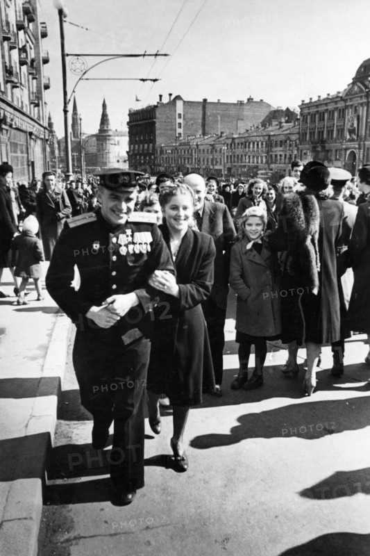 A red army soldier and his girlfriend on gorky street after the victory day celebrations in red square on may 9, 1945, the towers of the moscow kremlin can be seen in the background.