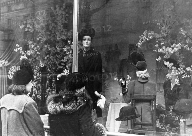 Two women looking at coats and hats on display in a window of the central department store in moscow, 1940s.