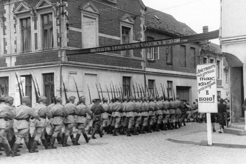 World war 2, men of a soviet garrison in germany marching to the drill grounds, july 1945, sign reads: 'approach learning the same way as one would approach going to battle,'.
