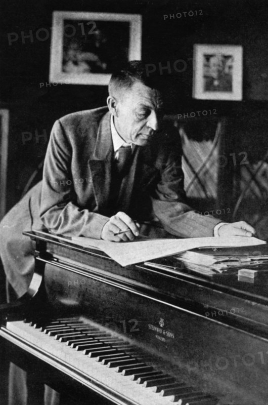 Russian composer, sergei v, rachmaninov, looking over a manuscript at his piano in the late 1920s.