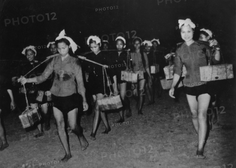 A women's unit carrying supplies to the south vietnam people's liberation army forces along the ho chi minh trail at night, vietnam war, 1968.