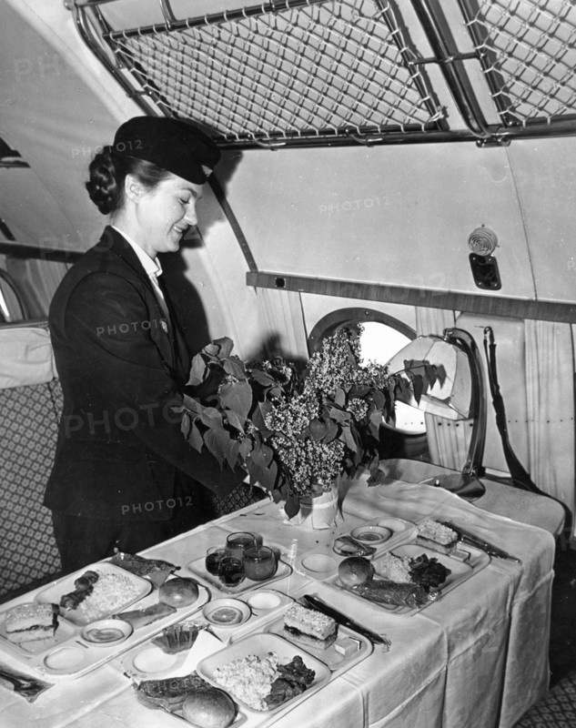 A stewardess placing flowers from khabarovsk on the dinner table aboard a tu-114 airliner (at the time, the world's largest), may 1959.