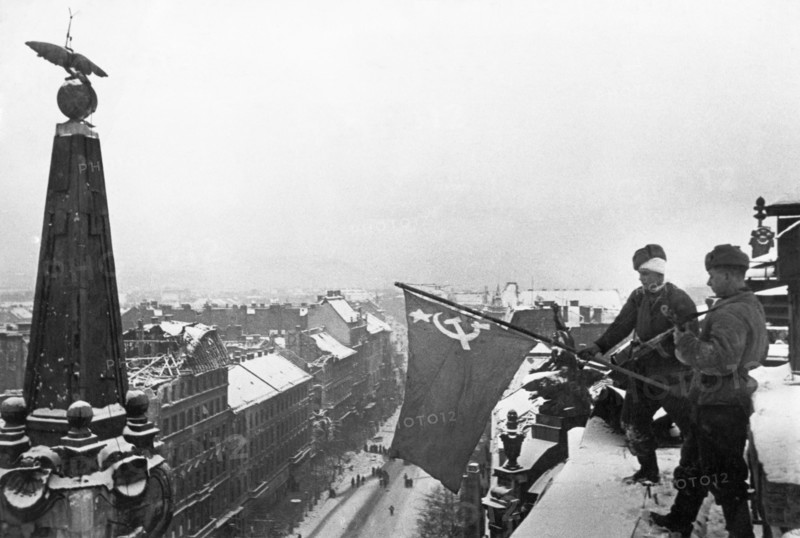 World war 2, soviet soldiers raising the flag of victory above a city building in budapest, hungary after the capture of the hungarian capital, february 1945.