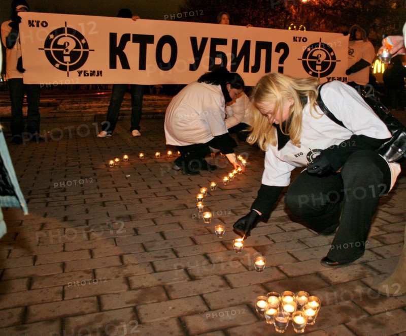 Mourners arrange lit candles into a large question mark in front of a banner reading 'who's the killer?' during a rally in pushkin square, marking the 40 day anniversary of anna politkovskaya's death, moscow, russia, november 15, 2006.