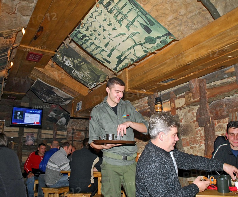 Waiter serving drinks at kryivka, a new cafe with the decor of a upa (ukrainian insurgent army) bunker, in the city of lvov (lviv), western ukraine,  october 2007.