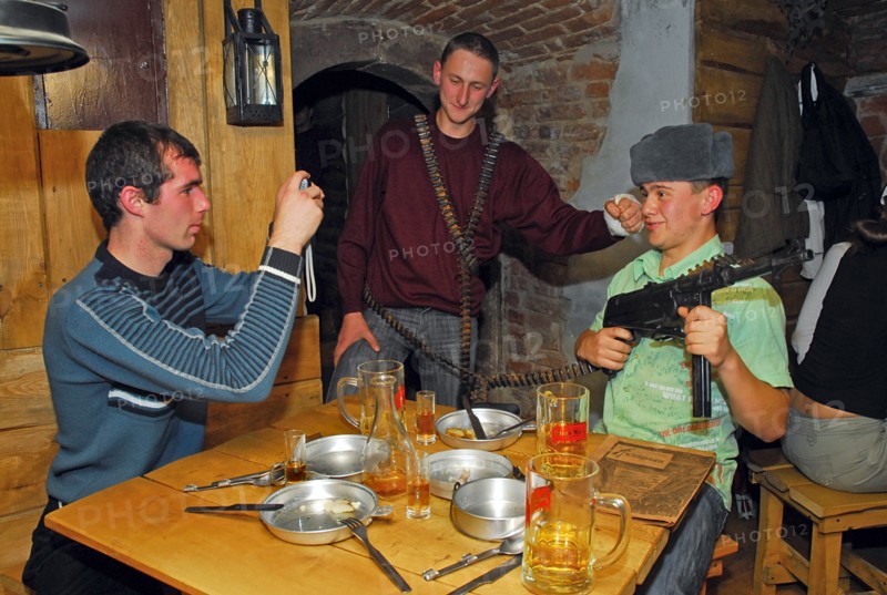 Young people with an assault rifle and an empty ammo belt pose for a photograph at kryivka, a new cafe with the decor of a upa (ukrainian insurgent army) bunker, in the city of lvov (lviv), western ukraine, october 2007.