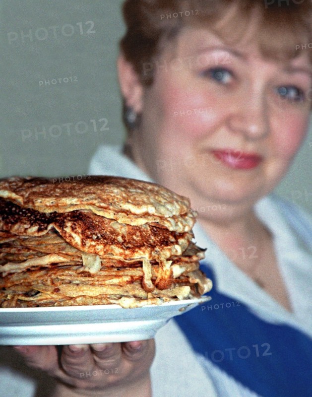 Yekaterinburg, russia, 3/13/02: yekaterina zasada, a resident of yekaterinburg, showing off a pile of bliny (pancakes) she has cooked for maslenitsa (shrovetide), which is celebrated this week, traditionally the delicious bliny are made of combined wheat and buckwheat flour and can be served with sour cream, honey, jam or red caviar.