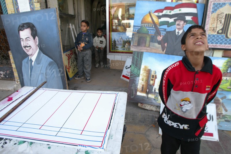 Baghdad, iraq, february 17 2003: a young resident of bagdad pictured viewing some works of a street artist in downtown the city.