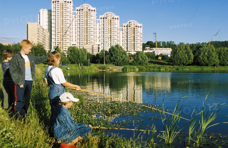 Kids fishing in a city pond in a residential district of moscow, aug, 2000.