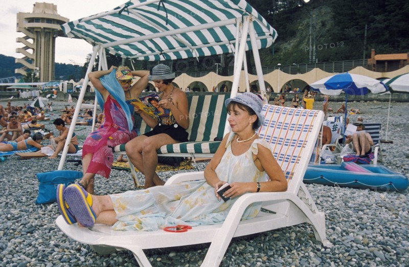 Vacationers enjoying the 'velvet season' (fall) on a pebble beach in sochi, the famous resort city on the black sea coast, krasnodar region, russia.