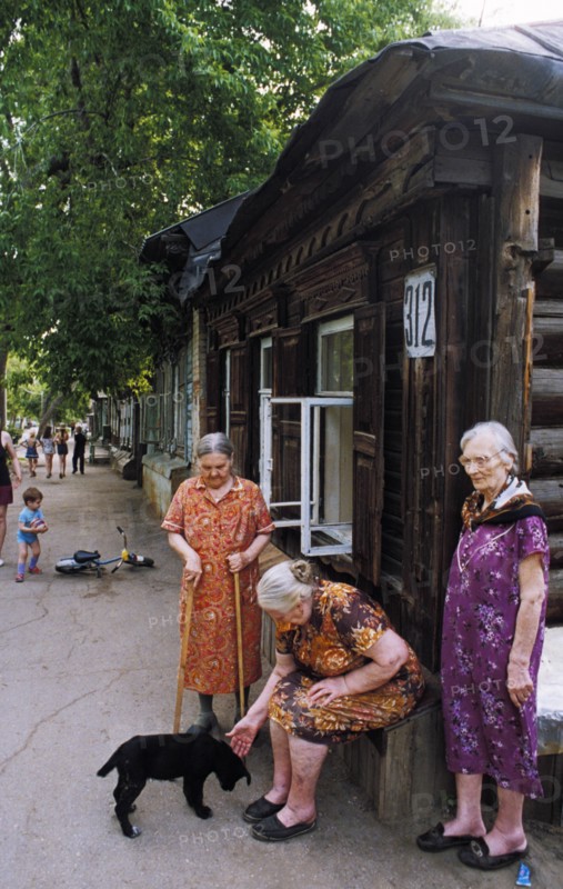 Elderly women in front of an old wooden house in a district in samara built in the19th century, russia.